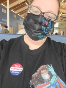 Woman wearing a black shirt and black mask with butterflies who has a 